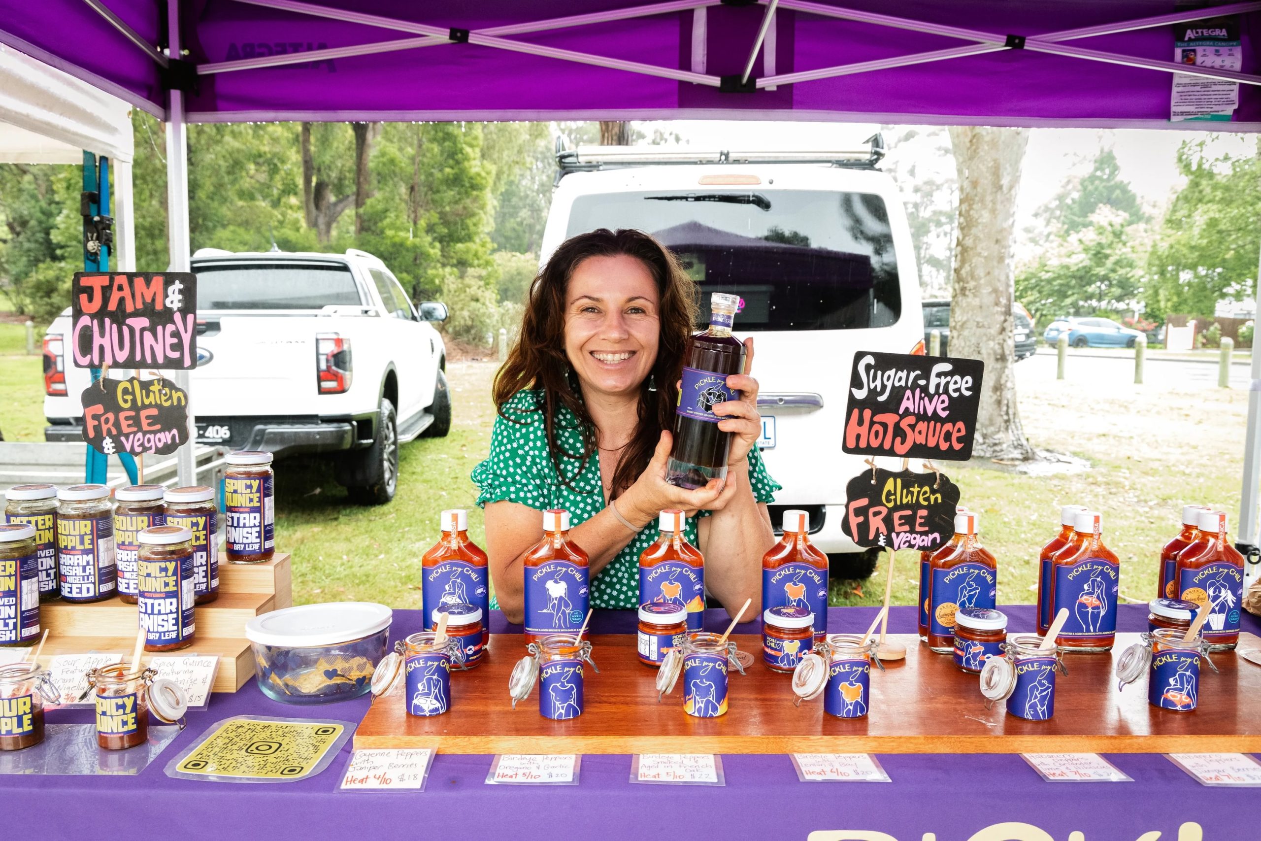 Owner of Pickle My Chili sitting at market stall with her chili sauces
