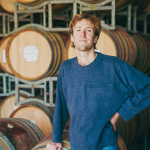 Dominic standing in front of wine barrels