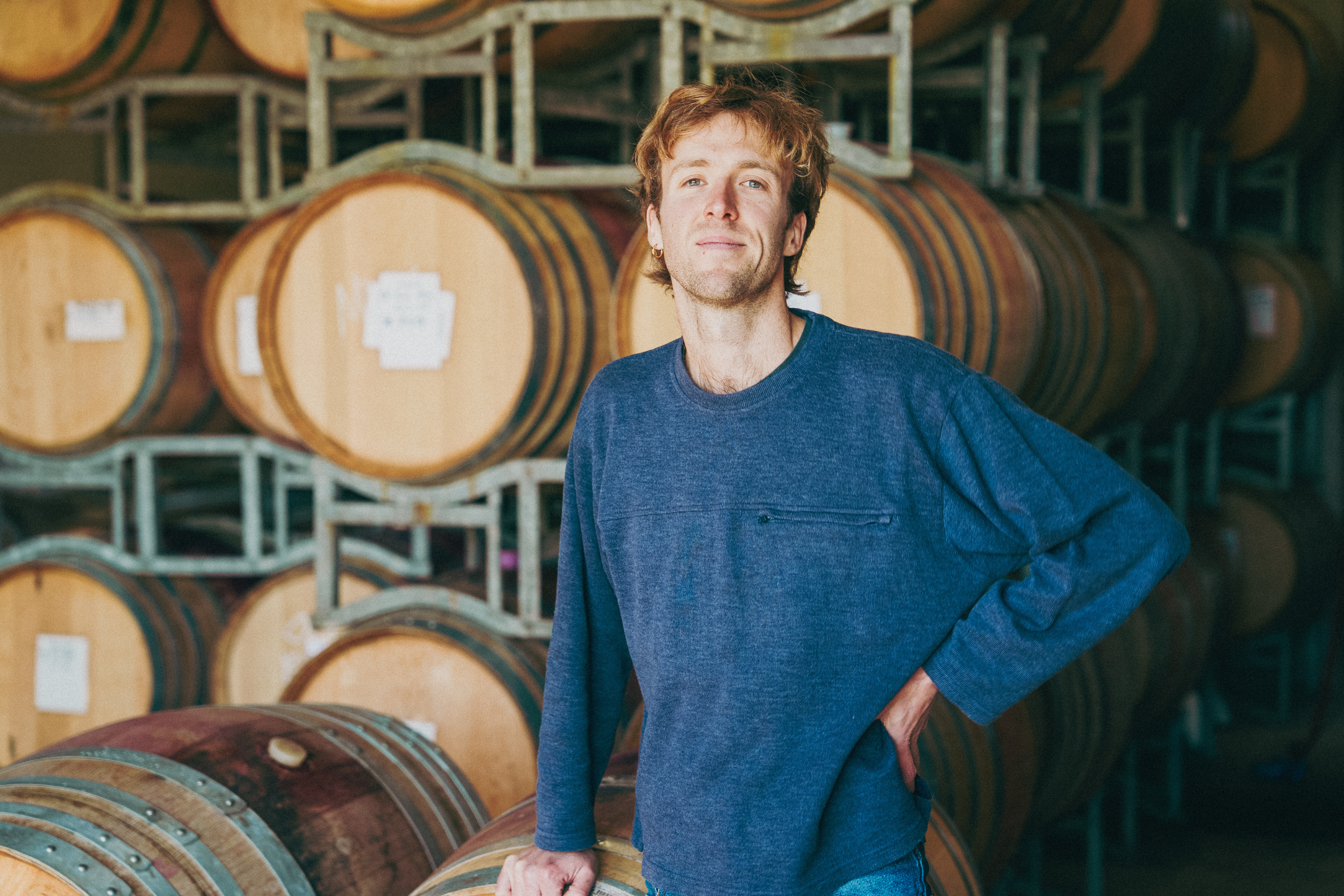 Dominic standing in front of wine barrels