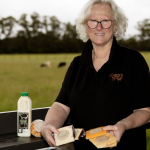 Kaye at Bassine Specialty Cheese holding a variety of their products