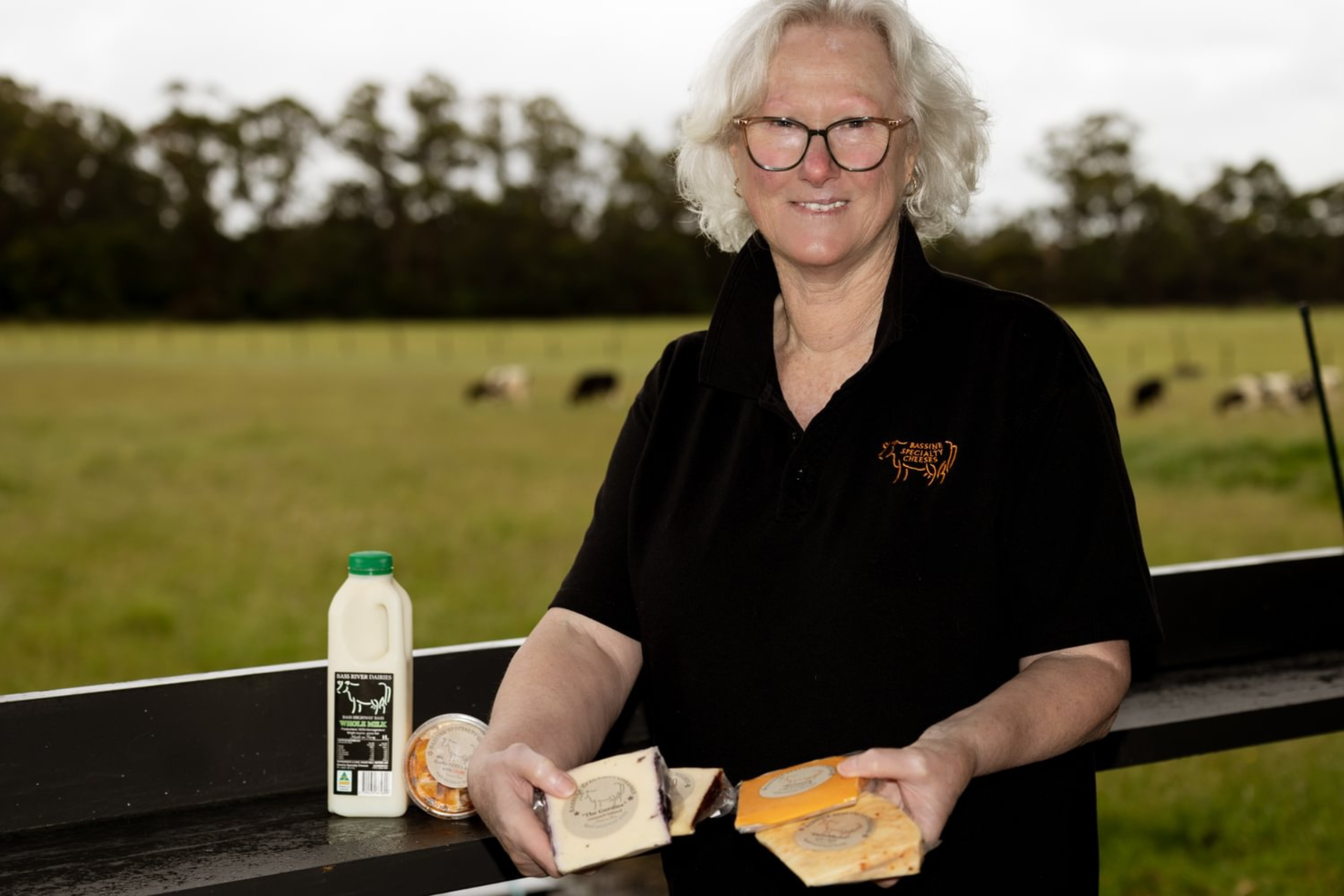 Kaye at Bassine Specialty Cheese holding a variety of their products